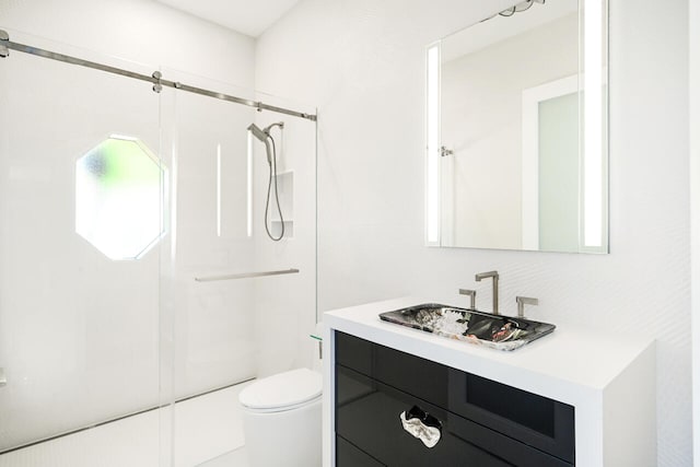 bathroom featuring a shower with shower door, vanity, and toilet