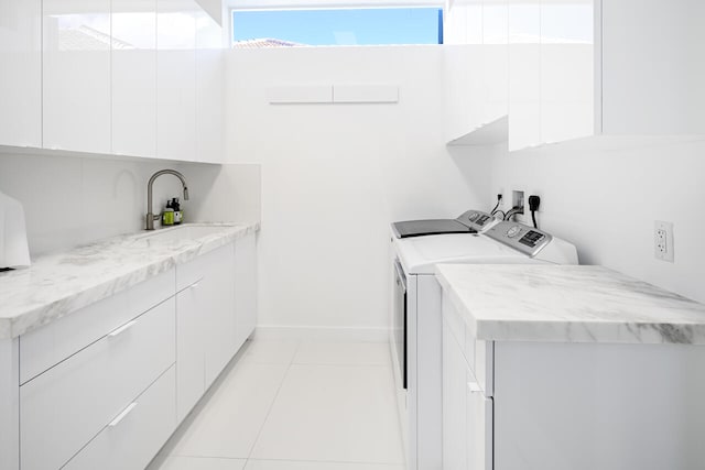 laundry area with light tile patterned floors, a sink, baseboards, cabinet space, and washing machine and clothes dryer