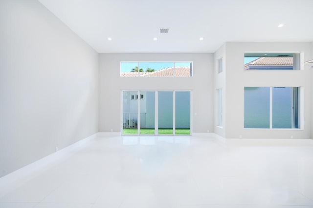 empty room with a towering ceiling, visible vents, and recessed lighting