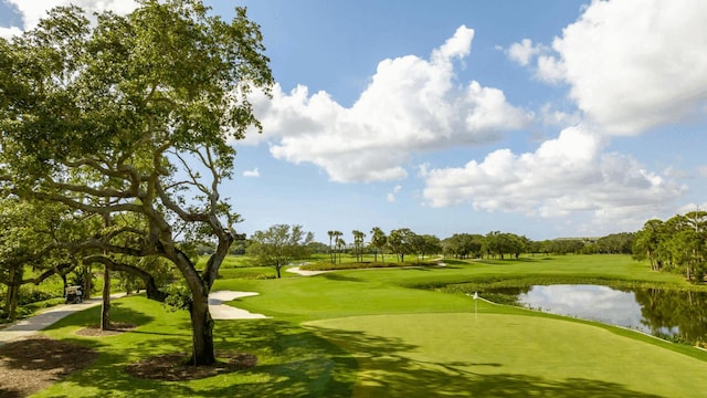 view of home's community with view of golf course, a water view, and a lawn