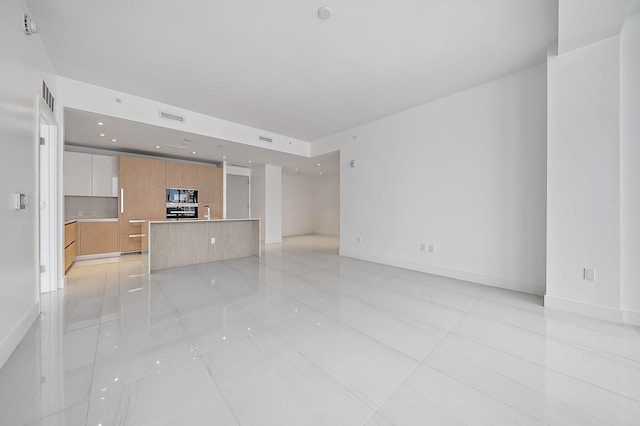 unfurnished living room with recessed lighting, visible vents, a sink, and baseboards