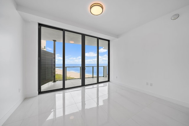 spare room featuring baseboards, a water view, and tile patterned floors