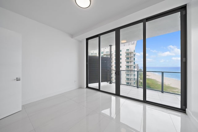 spare room with a water view, tile patterned floors, and baseboards