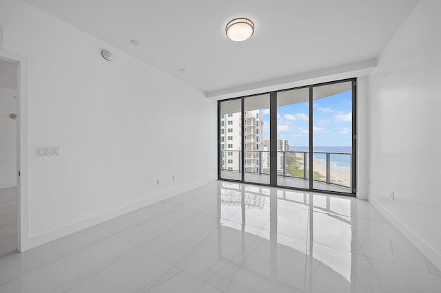 spare room with a water view, tile patterned floors, and baseboards