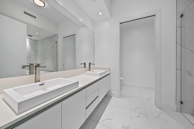 full bath featuring marble finish floor, a marble finish shower, visible vents, and a sink