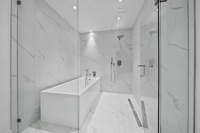 bathroom with a freestanding tub, a marble finish shower, visible vents, and tile walls