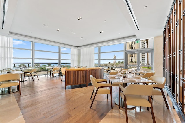 dining area featuring light wood-type flooring, a raised ceiling, and floor to ceiling windows