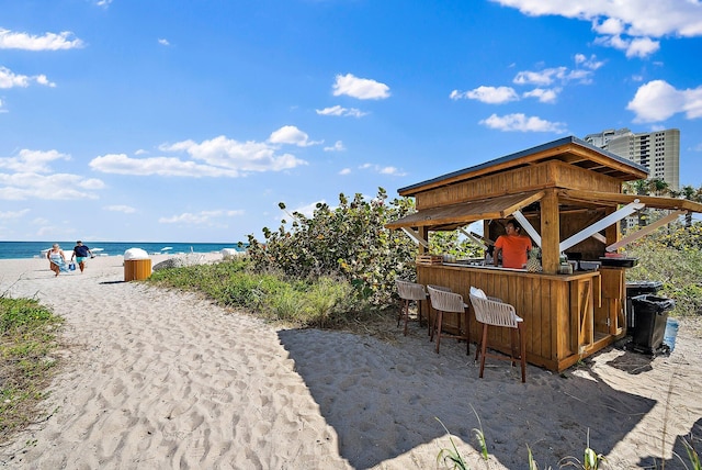 view of patio with a view of the beach, a water view, and outdoor dry bar