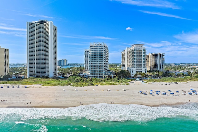 drone / aerial view featuring a view of city, a water view, and a beach view