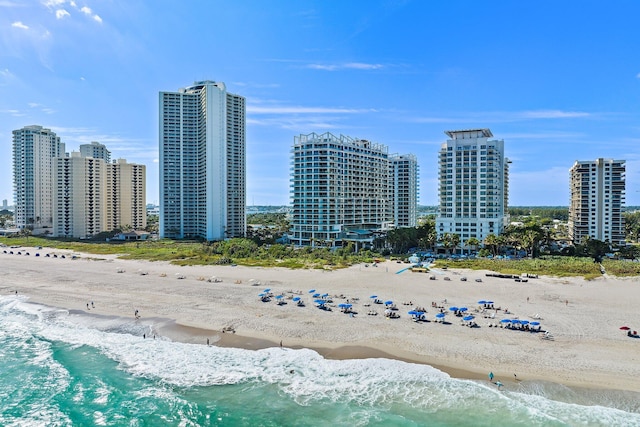 drone / aerial view featuring a view of the beach, a water view, and a view of city