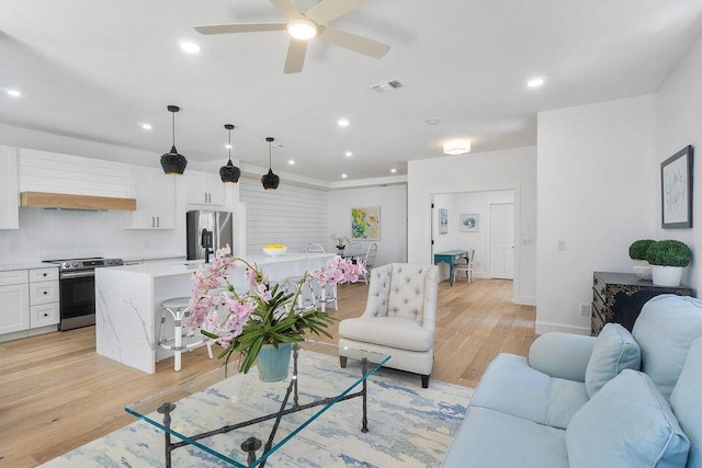 living room featuring light wood finished floors, ceiling fan, baseboards, and recessed lighting