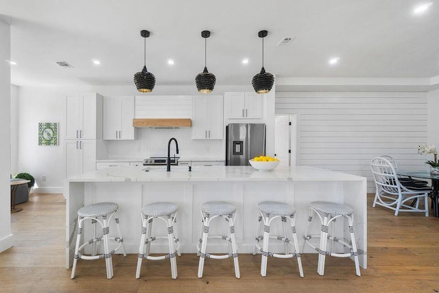 kitchen featuring white cabinetry, stainless steel fridge, visible vents, and a spacious island