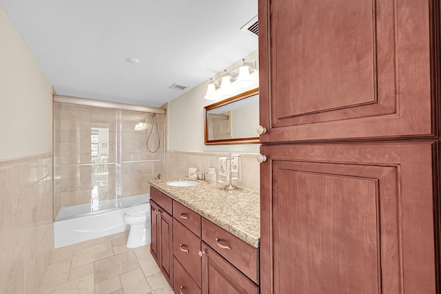 bathroom featuring toilet, wainscoting, visible vents, and tile walls