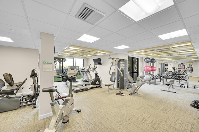 exercise room with carpet floors, a paneled ceiling, visible vents, and baseboards