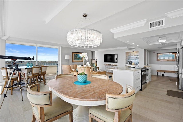 dining space with a wainscoted wall, light wood-style floors, visible vents, and crown molding