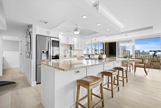 kitchen with visible vents, decorative backsplash, a raised ceiling, light wood-type flooring, and stainless steel refrigerator with ice dispenser