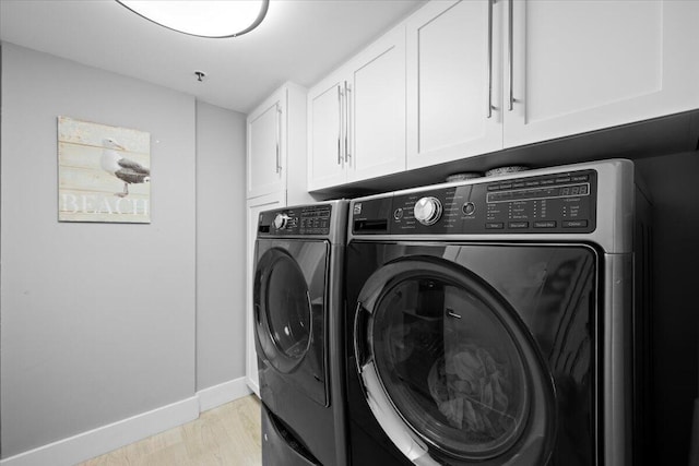 clothes washing area with light wood-style floors, cabinet space, independent washer and dryer, and baseboards