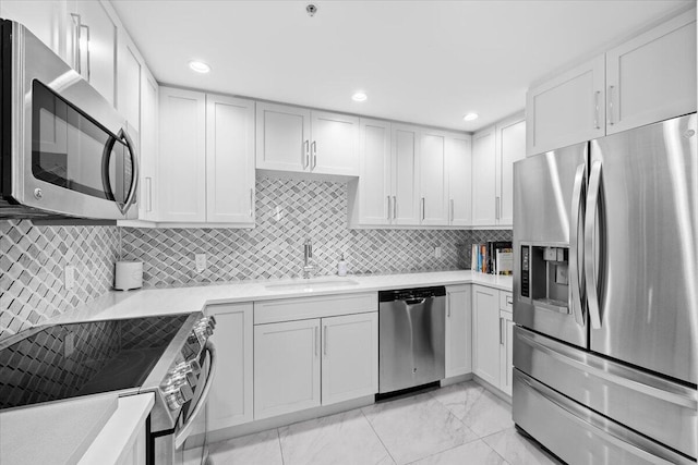 kitchen with stainless steel appliances, a sink, marble finish floor, light countertops, and decorative backsplash