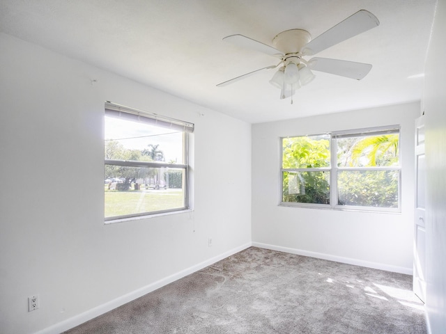 carpeted empty room with ceiling fan and baseboards