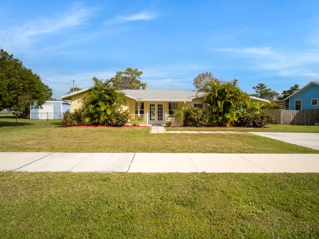 ranch-style home featuring stucco siding, fence, a front lawn, and french doors