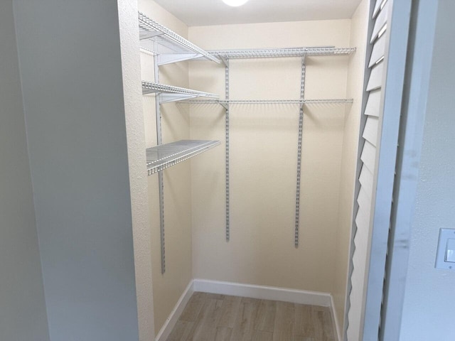 walk in closet with wood finished floors