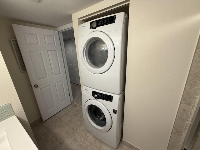 laundry room with laundry area, baseboards, stacked washing maching and dryer, and light tile patterned floors