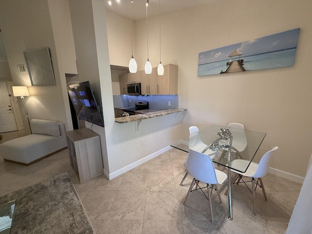 dining room with a towering ceiling, visible vents, and baseboards