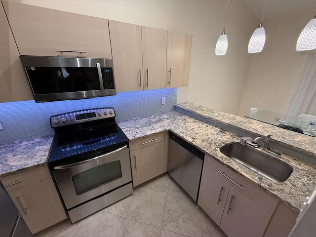 kitchen featuring light stone counters, backsplash, appliances with stainless steel finishes, a sink, and a peninsula