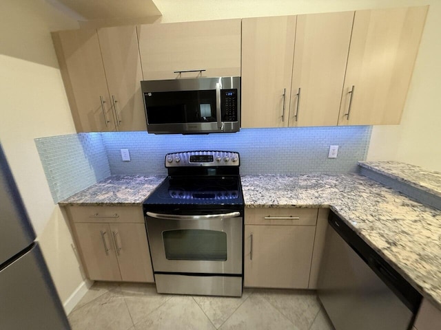 kitchen featuring stainless steel appliances, light stone counters, and tasteful backsplash