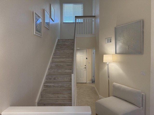 staircase with wood finished floors, visible vents, and baseboards