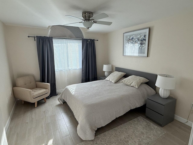 bedroom with light wood finished floors, a ceiling fan, and baseboards