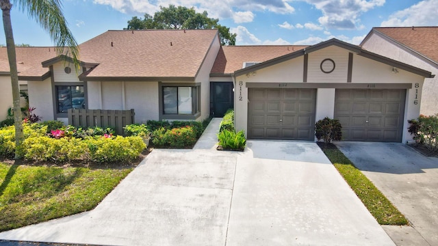 view of front of home with a garage, concrete driveway, roof with shingles, and stucco siding