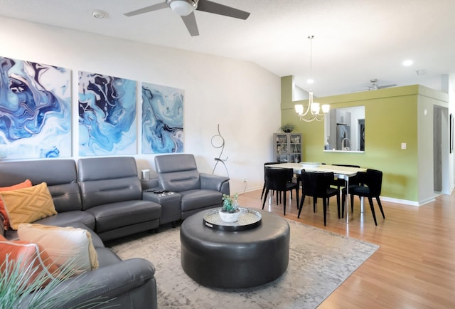 living area featuring vaulted ceiling, light wood-style flooring, baseboards, and ceiling fan with notable chandelier