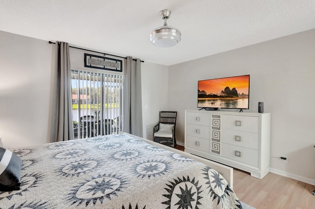 bedroom featuring access to outside, baseboards, and wood finished floors