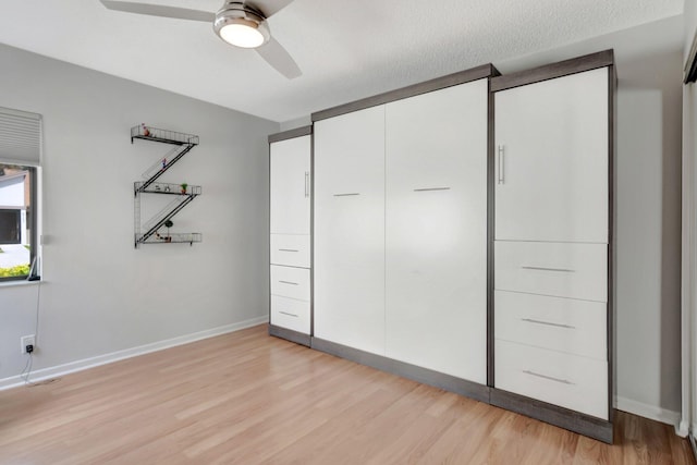 unfurnished bedroom featuring baseboards, ceiling fan, a closet, and light wood-style floors