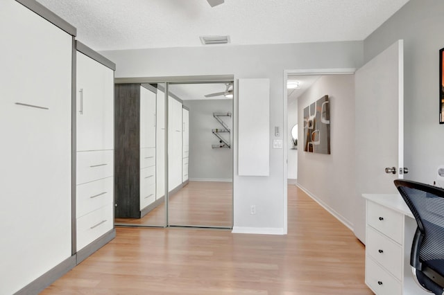 unfurnished bedroom with a closet, visible vents, a textured ceiling, light wood-type flooring, and baseboards