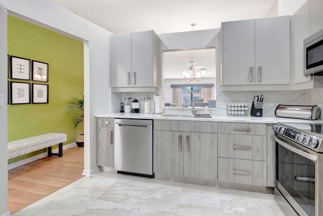 kitchen featuring light countertops, gray cabinetry, appliances with stainless steel finishes, a sink, and modern cabinets