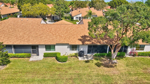 rear view of property with a shingled roof, a residential view, and a lawn