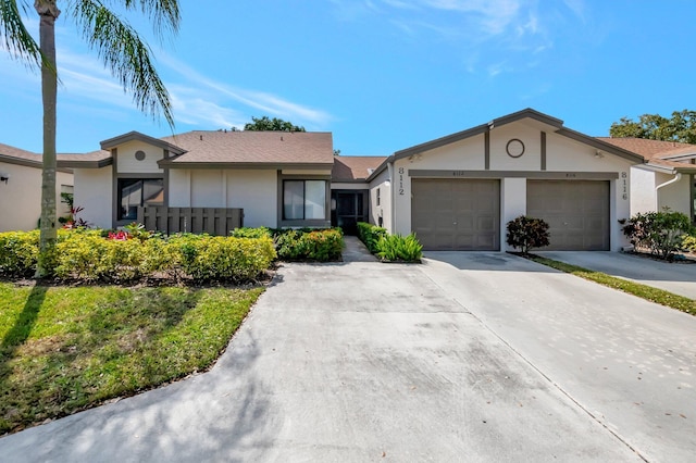 ranch-style home featuring concrete driveway, an attached garage, and stucco siding