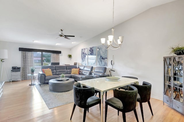 dining area featuring light wood-style floors, vaulted ceiling, and ceiling fan with notable chandelier