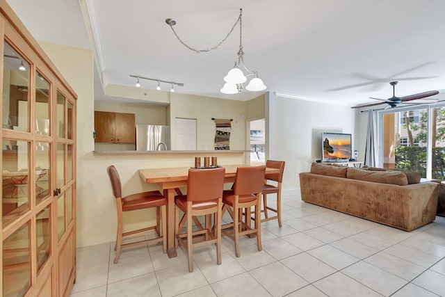 dining space with light tile patterned floors, ceiling fan with notable chandelier, and rail lighting