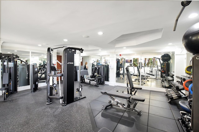 workout area featuring a raised ceiling and recessed lighting