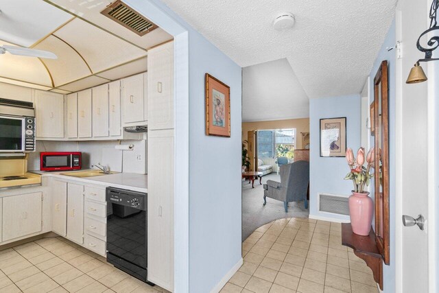 kitchen featuring black dishwasher, light countertops, light tile patterned flooring, and white cabinets