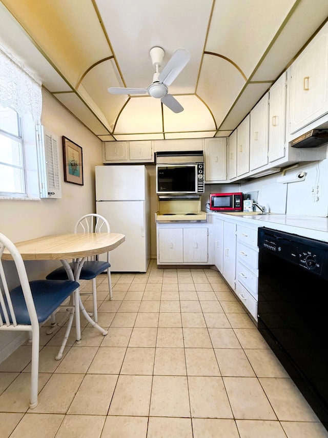 kitchen featuring light countertops, stainless steel microwave, freestanding refrigerator, light tile patterned flooring, and dishwasher