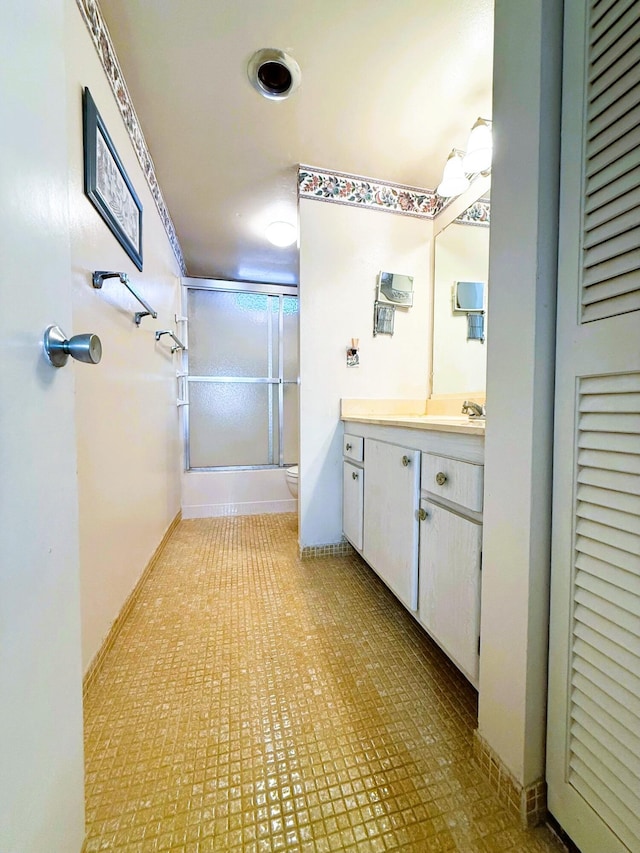 full bath featuring toilet, bath / shower combo with glass door, vanity, and baseboards