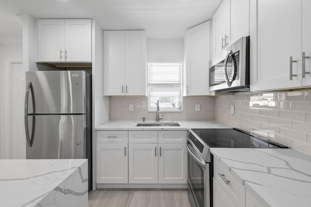 kitchen with appliances with stainless steel finishes, a sink, and white cabinetry
