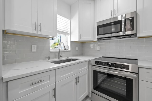 kitchen with stainless steel appliances, a sink, white cabinetry, and tasteful backsplash