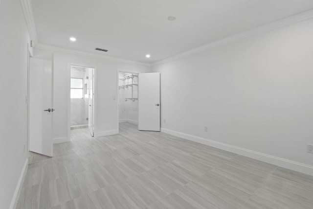 unfurnished bedroom featuring ornamental molding, baseboards, recessed lighting, a walk in closet, and ensuite bathroom