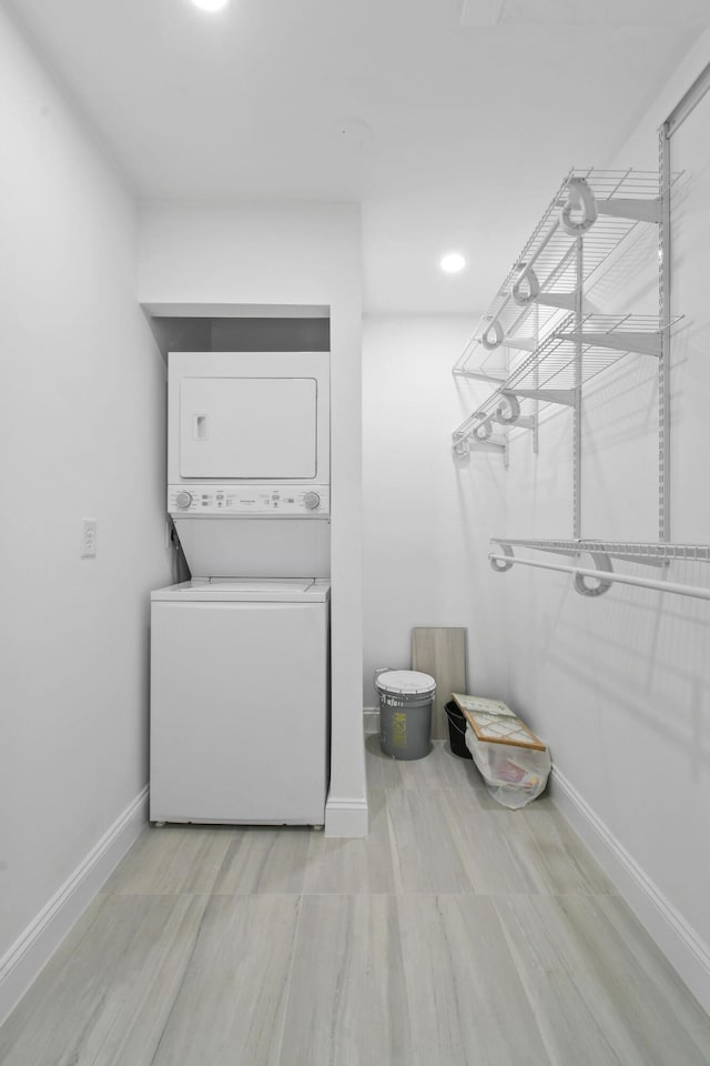 washroom with estacked washer and dryer and baseboards