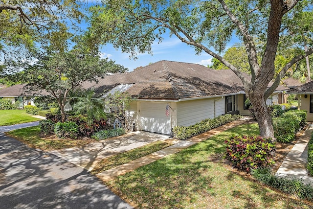 view of front of house with an attached garage, concrete driveway, and a front lawn